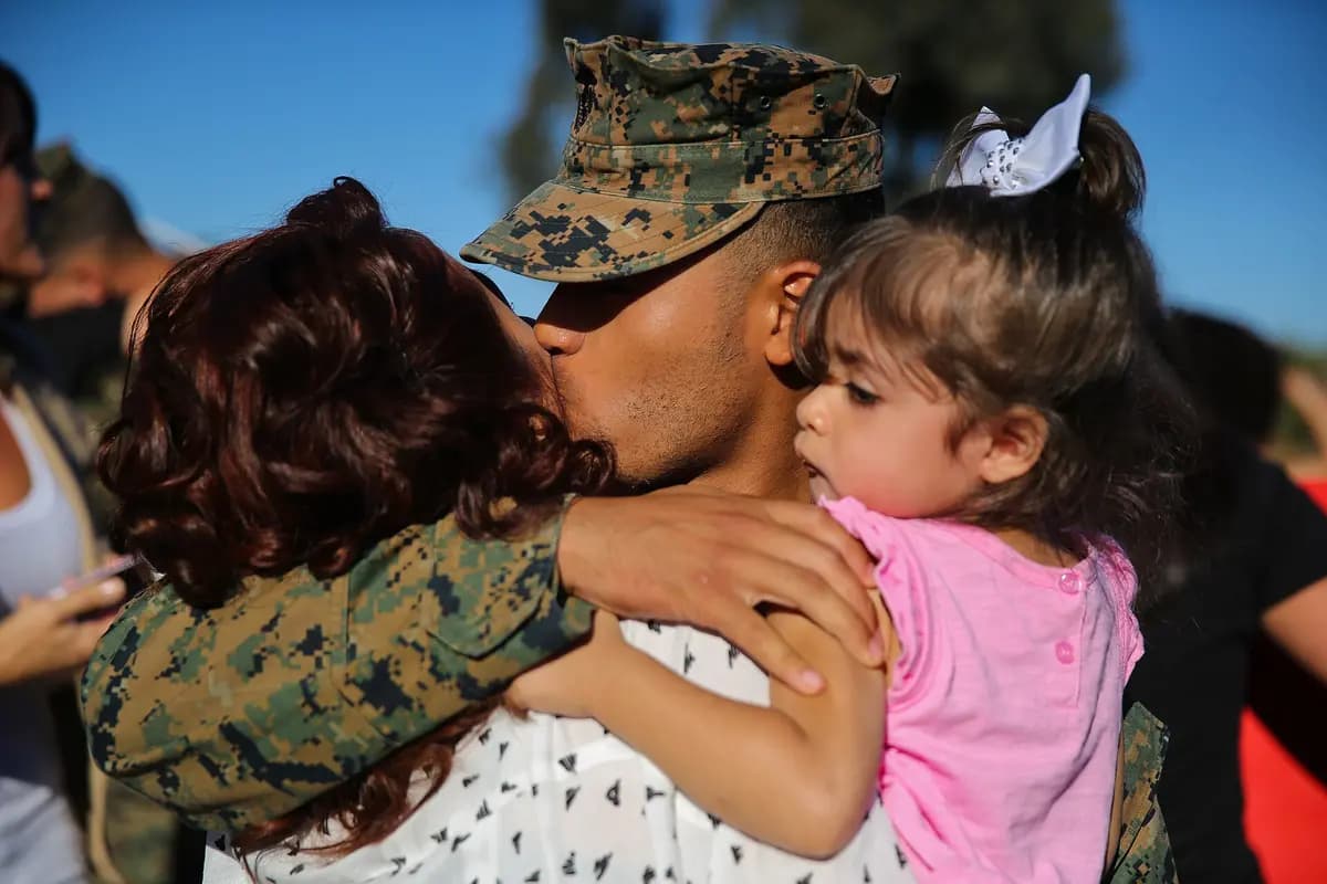 A Marine greeting his wife and young daughter after returning from a six-month deployment